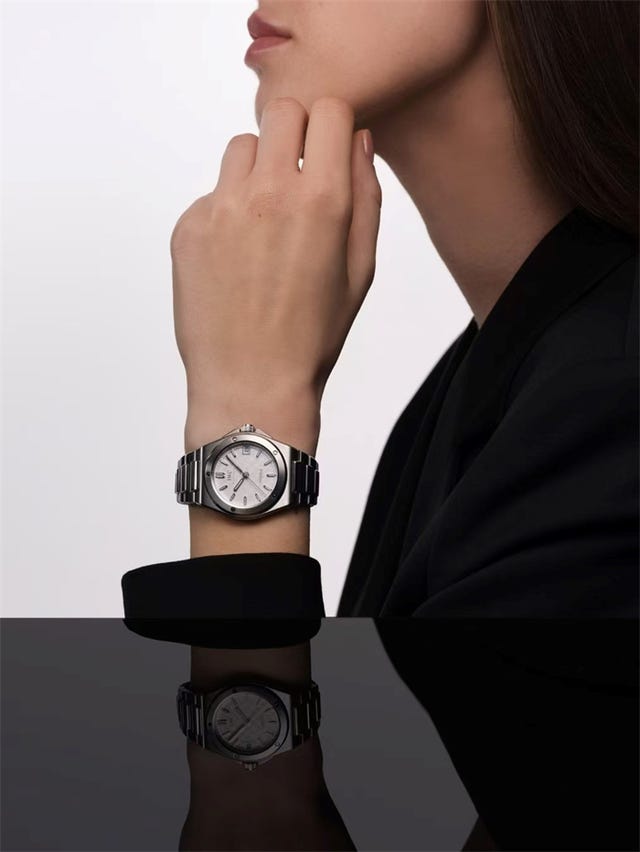 watch worn on a models wrist showcasing its design and reflecting on a surface