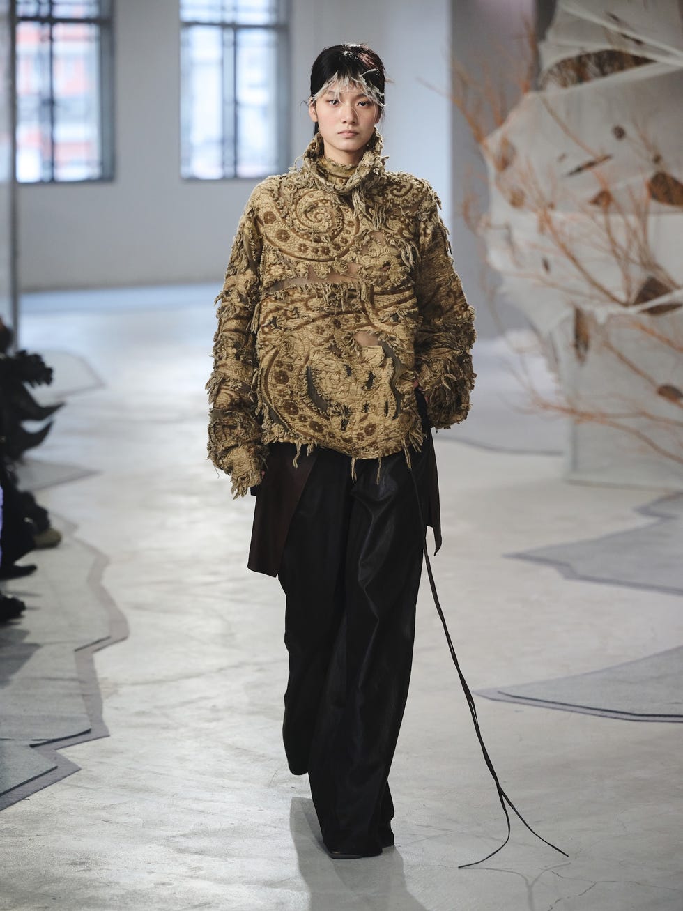 fashion model walking on a runway wearing a textured outfit