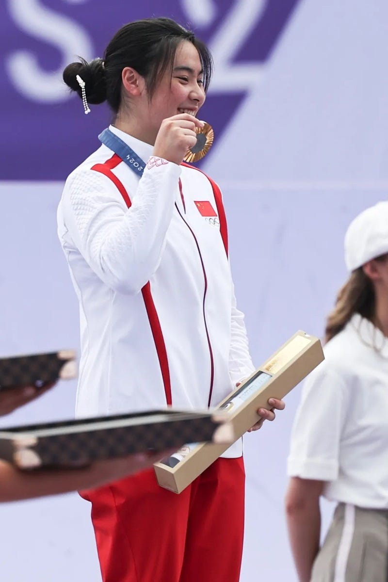 a person in a white suit holding a microphone and a paper