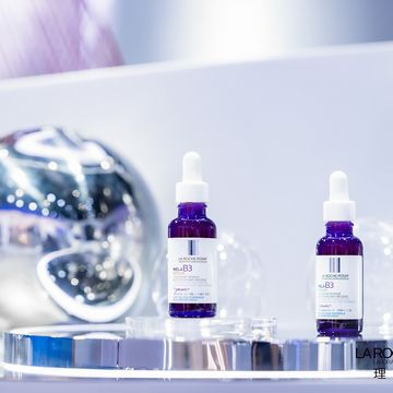 Two serum bottles on a reflective display with a shiny sphere in the background