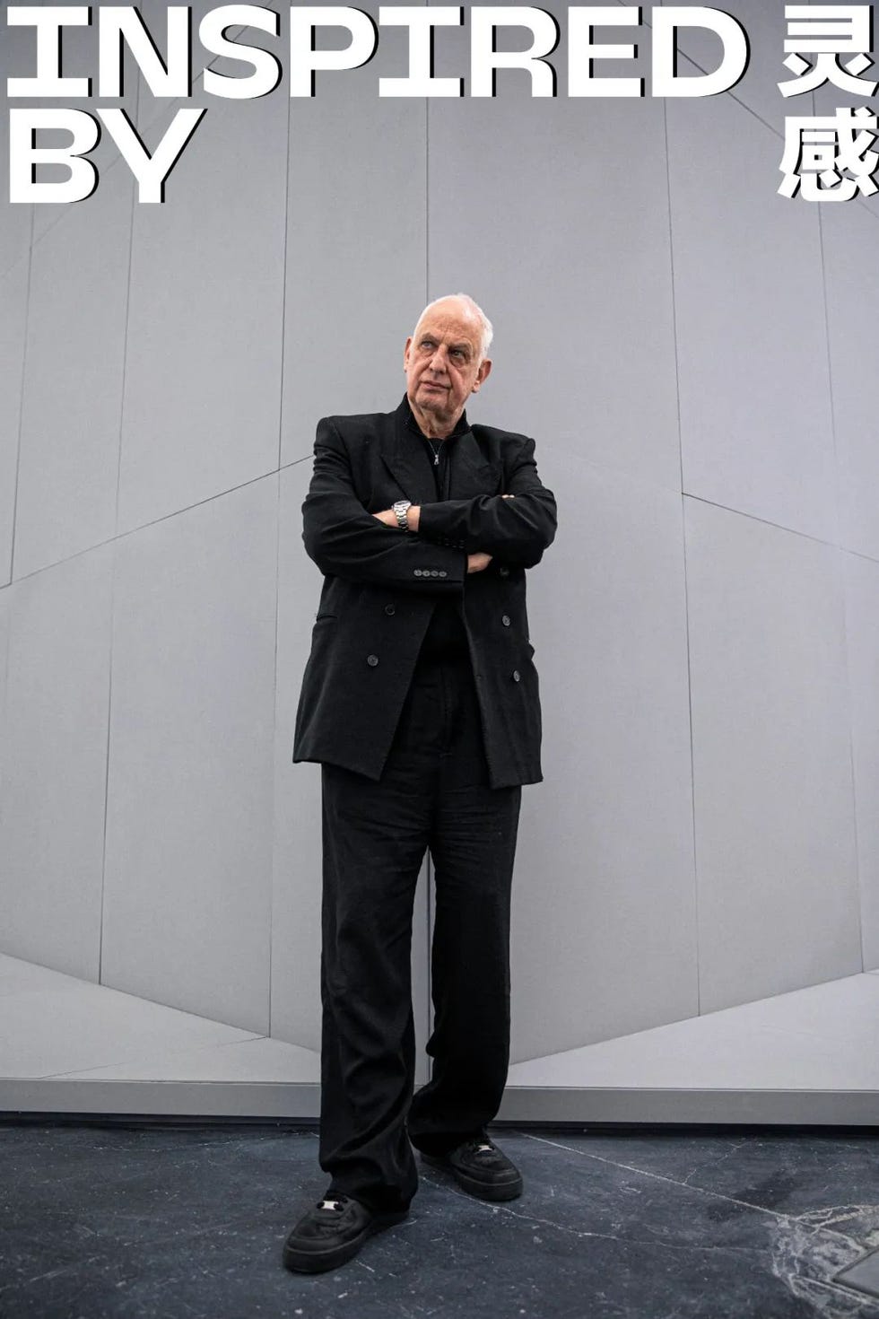 person standing confidently against a textured gray background with the text inspired by above