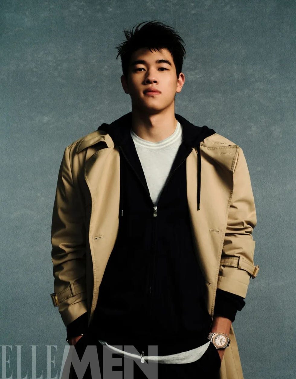 a young man in a fashionable outfit with a neutral background