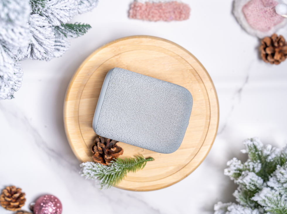 portable speaker placed on a wooden platter surrounded by holiday decorations