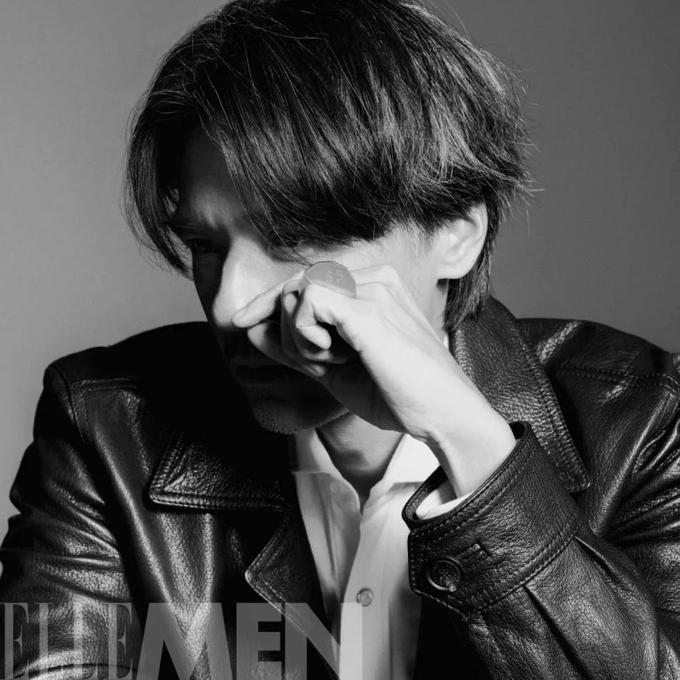 a person wearing a leather jacket partially obscured with a focus on their hand and attire