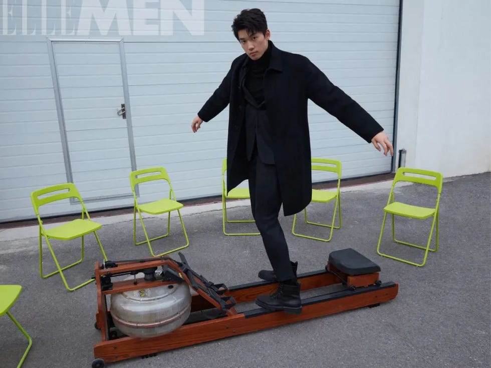 person balancing on a rowing machine with green chairs around