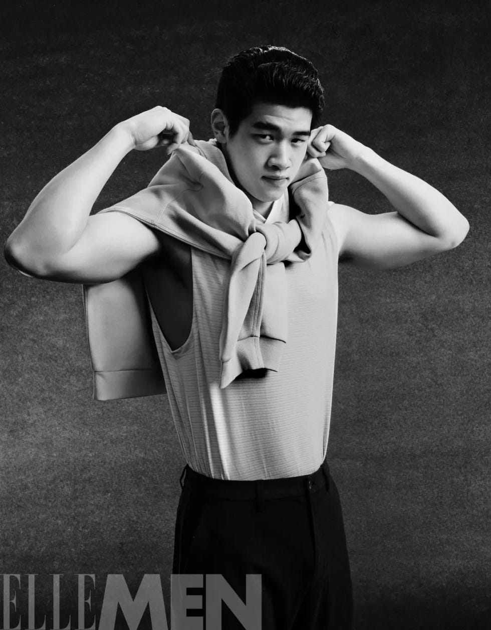 a person posing with a sweater draped around their shoulders showcasing a muscular physique