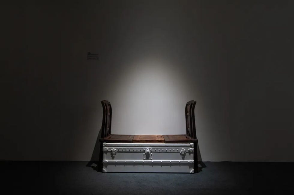 seating arrangement featuring a bench with two backrest chairs positioned on a dark floor in a spotlight