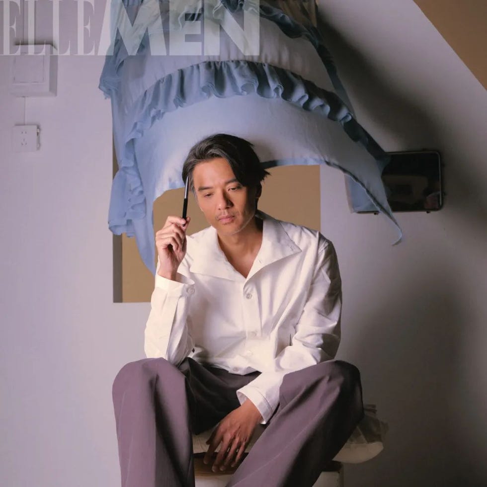 a person holding a pen while seated with a blue ruffled fabric draped above