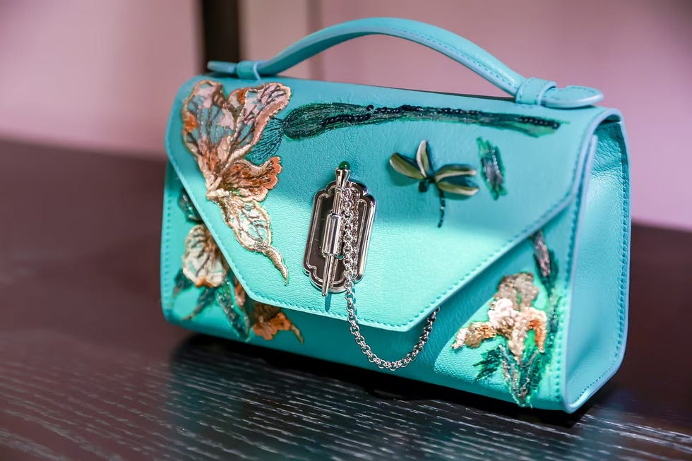 stylish turquoise handbag with floral embroidery and decorative elements