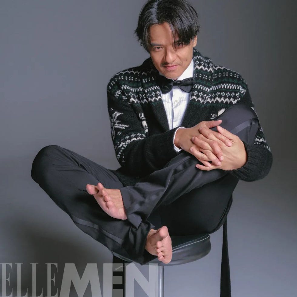 a seated man in a stylish outfit displaying a relaxed pose