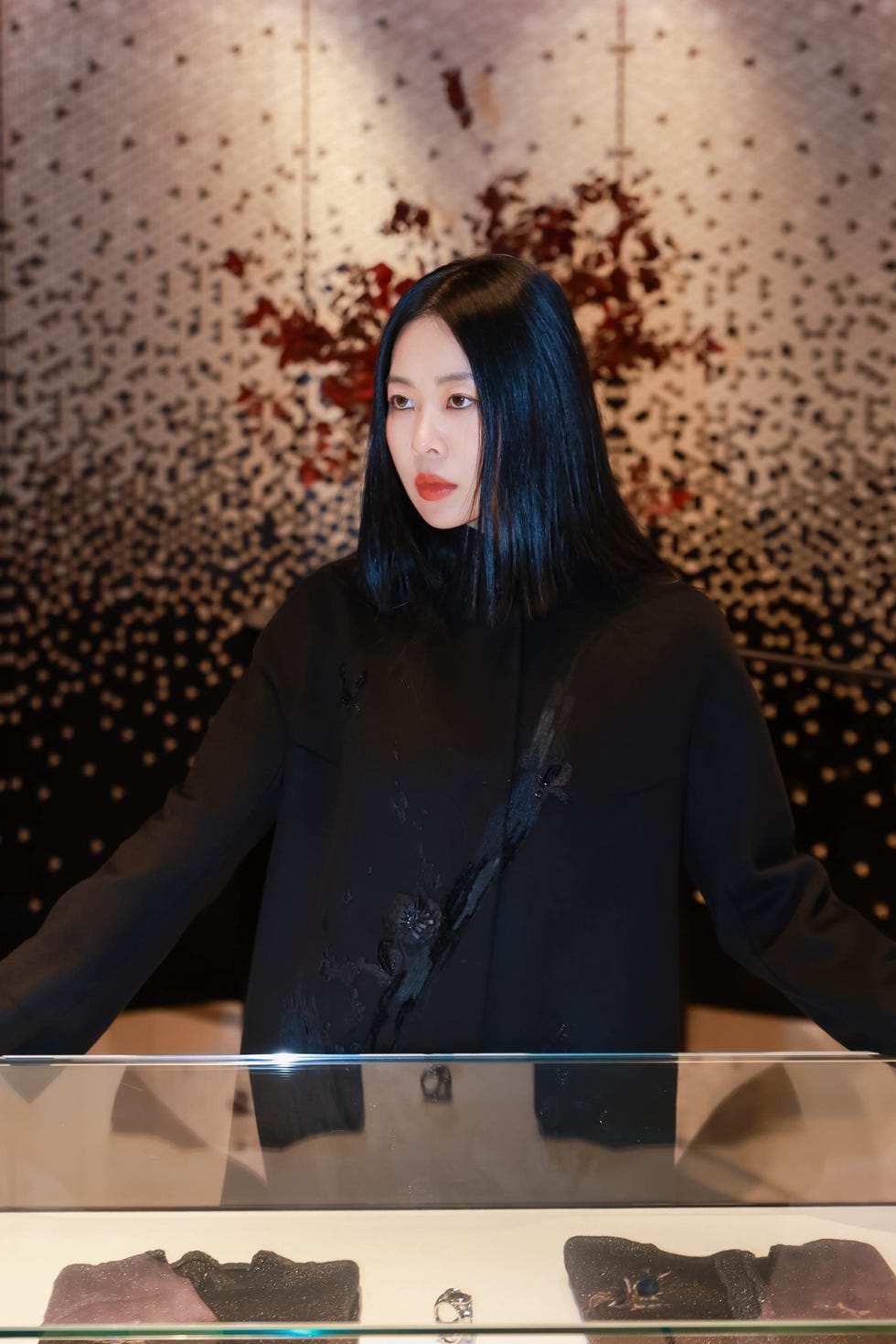 person standing in front of a display case with various textured cloth pieces