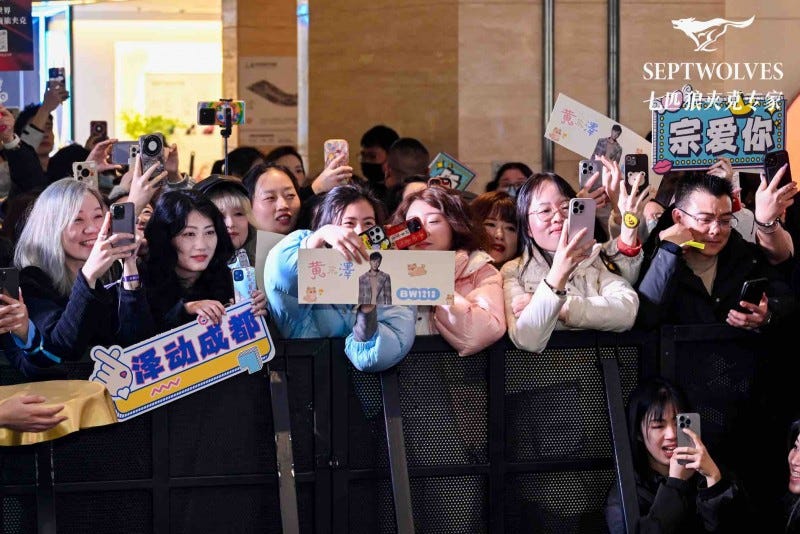 crowd of fans holding signs and smartphones at an event