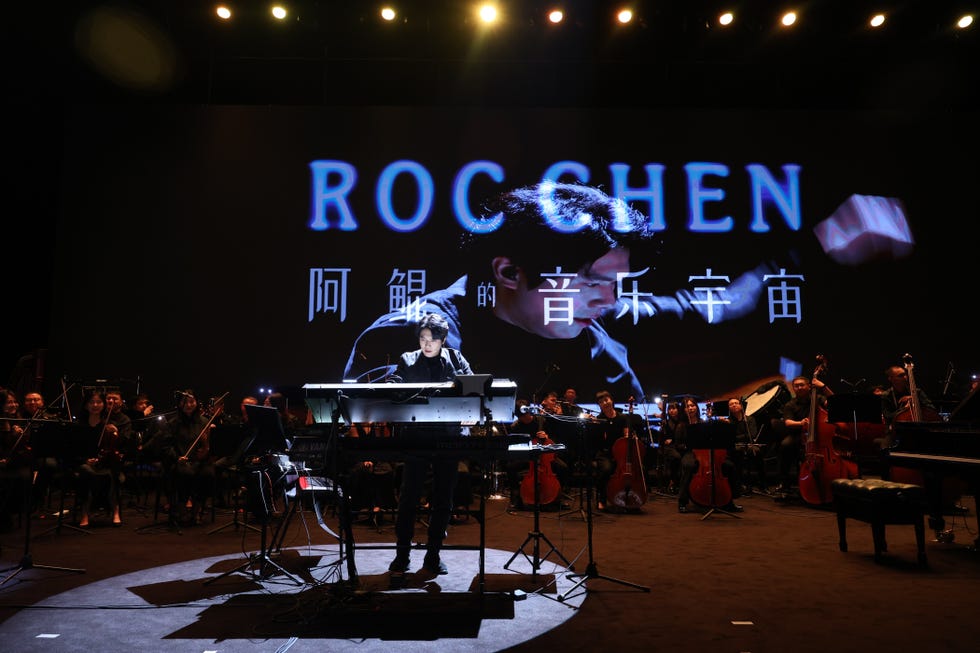 live music performance featuring a musician at a keyboard with an orchestra in the background