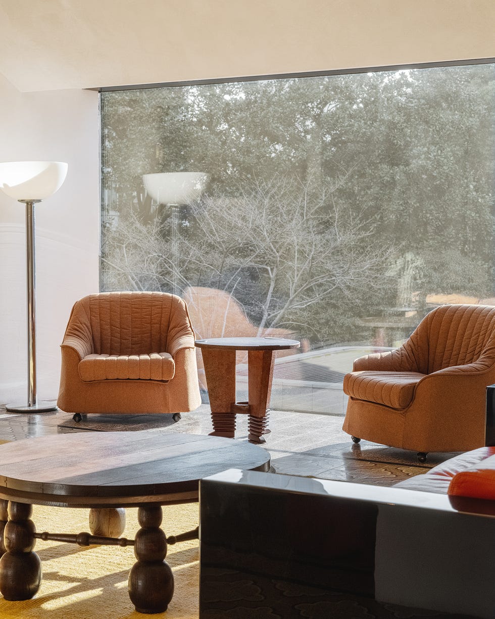 modern living room with two orange chairs a table and a large window