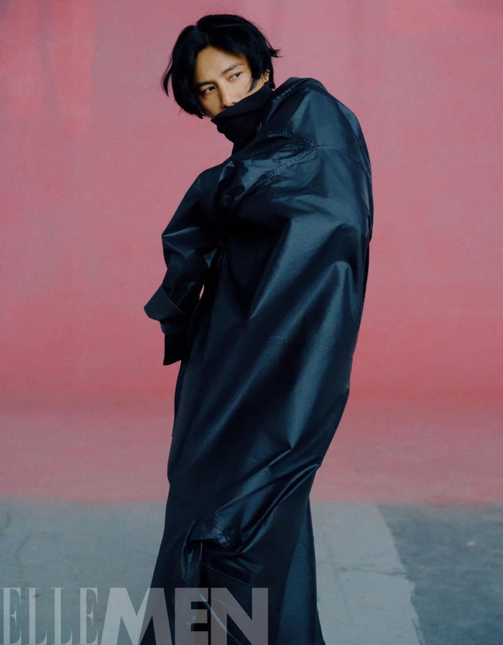 fashion model wearing a black oversized garment against a colorful backdrop