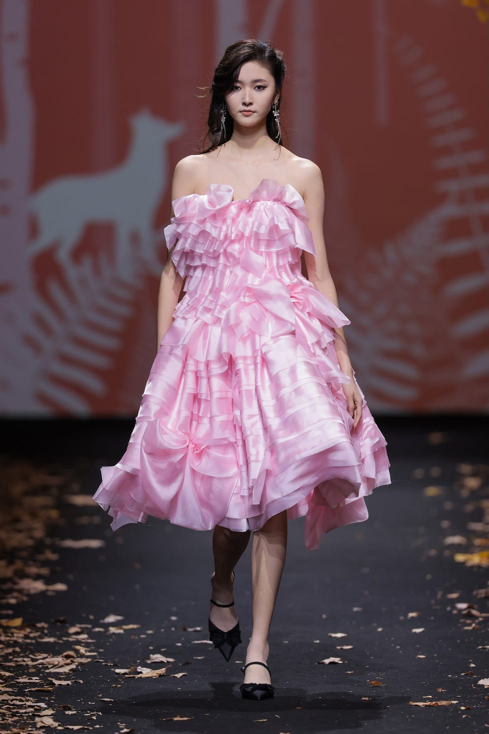 model showcasing a ruffled pink dress on the runway