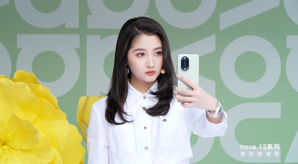 a person holding a smartphone and taking a selfie against a decorative background with large yellow flowers