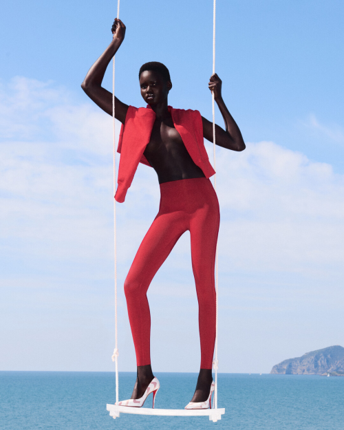 model posing on a swing against a beach backdrop