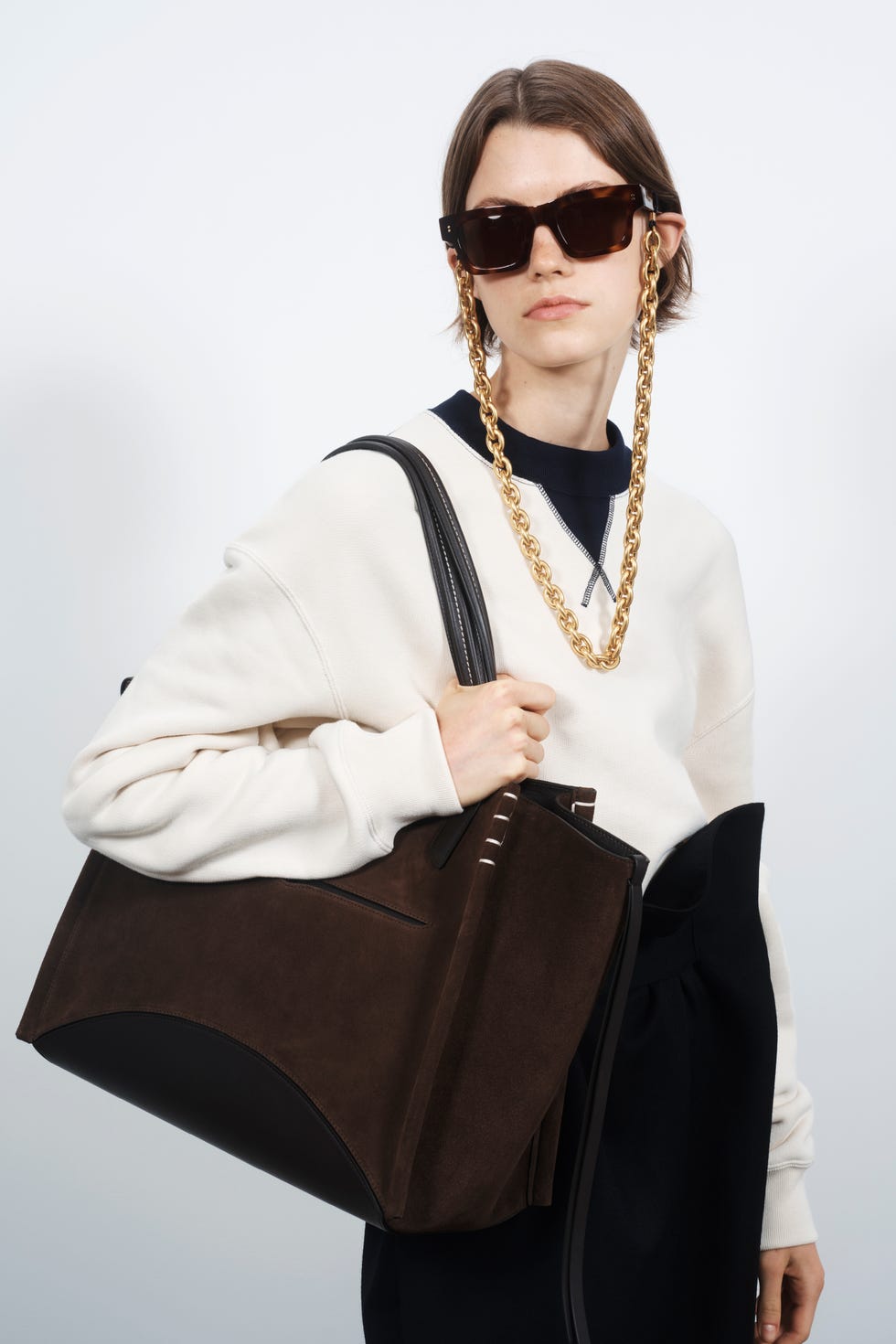 person holding a large brown suede tote bag with a distinctive design
