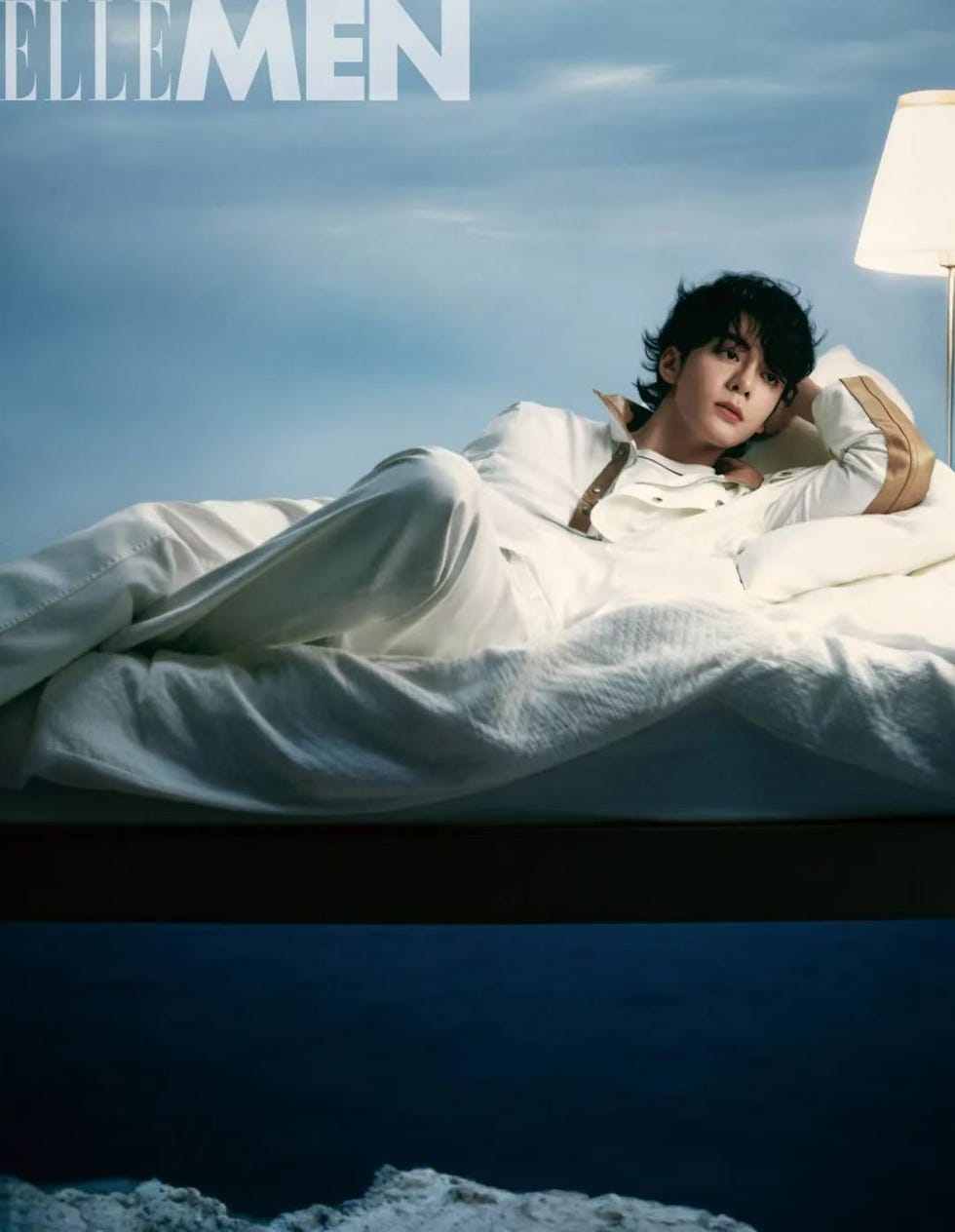 a person lounging on a bed with a serene background and a table lamp