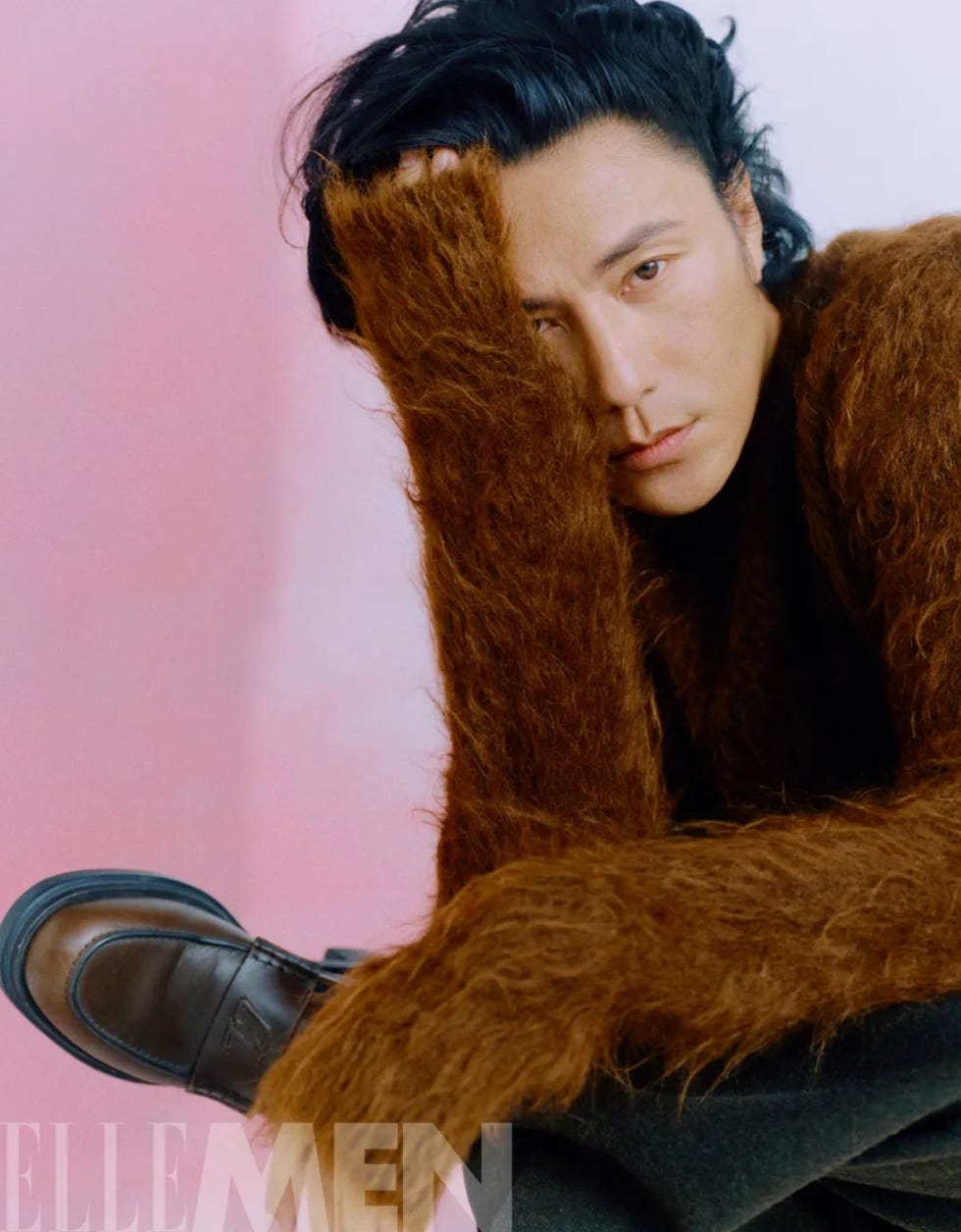 a person sitting with their head covered by a fuzzy hand showcasing a contemporary fashion style