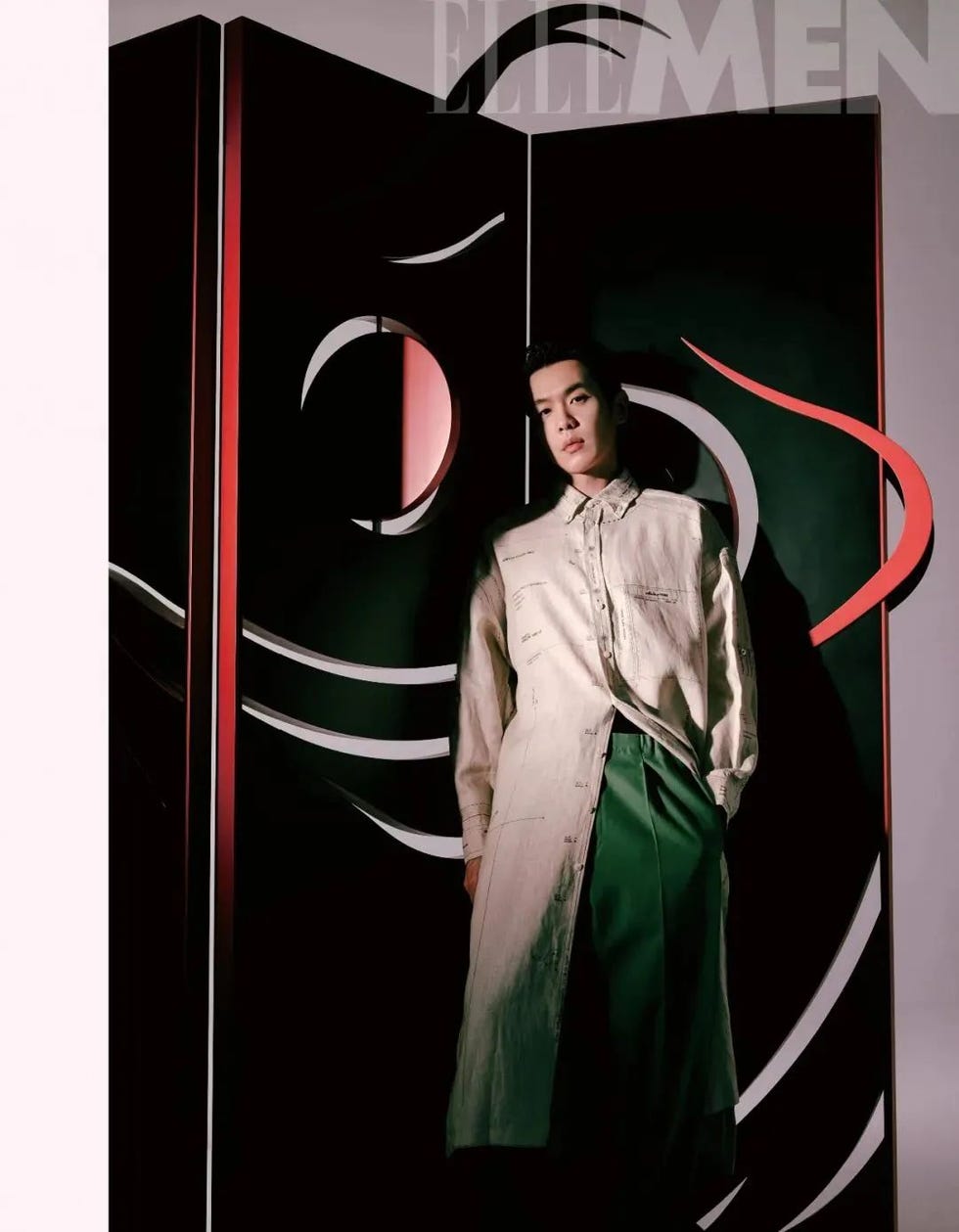 a person standing adjacent to an artistic backdrop featuring a stylized face design