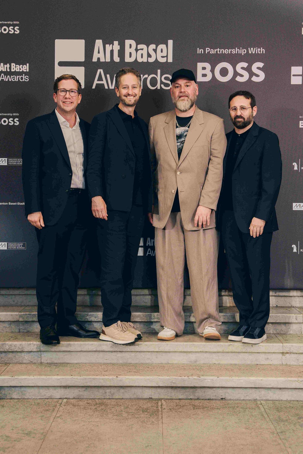 four individuals posing on a staircase at an event related to art basel
