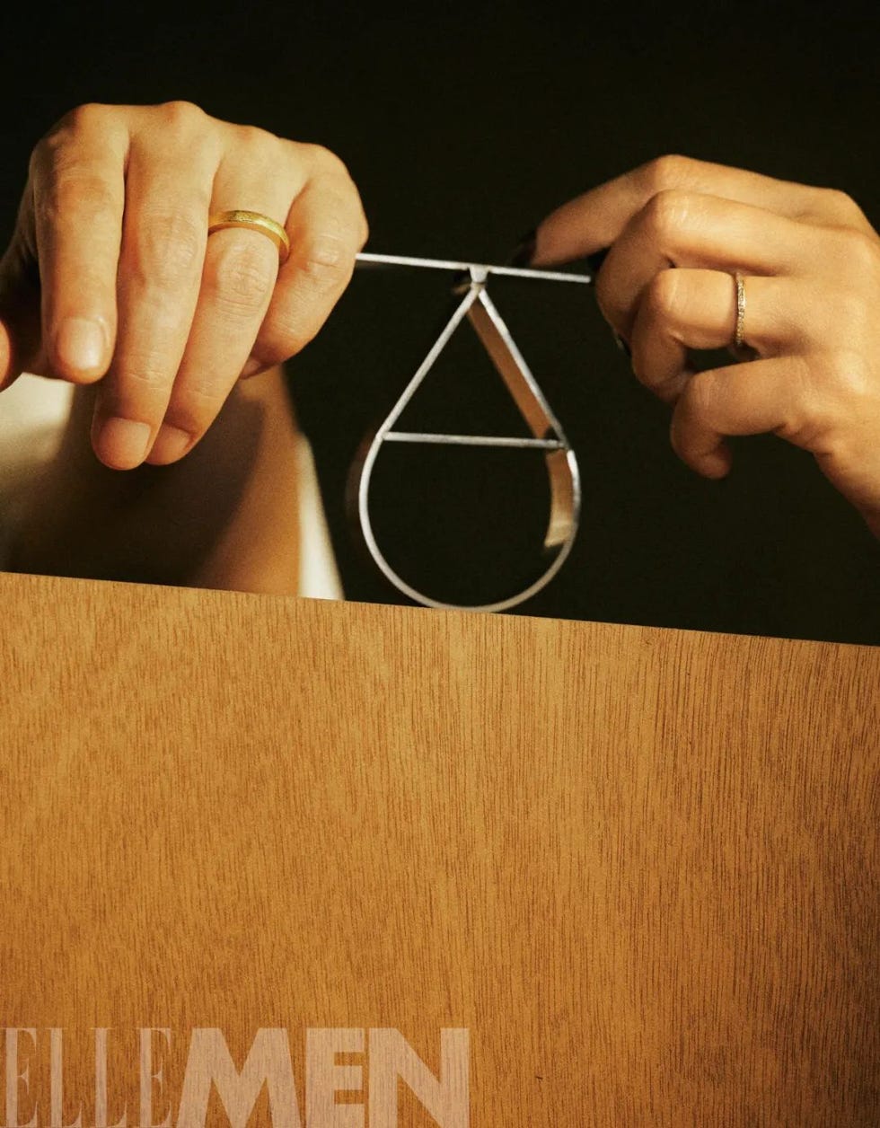 hands holding a metallic object resembling a drop shape
