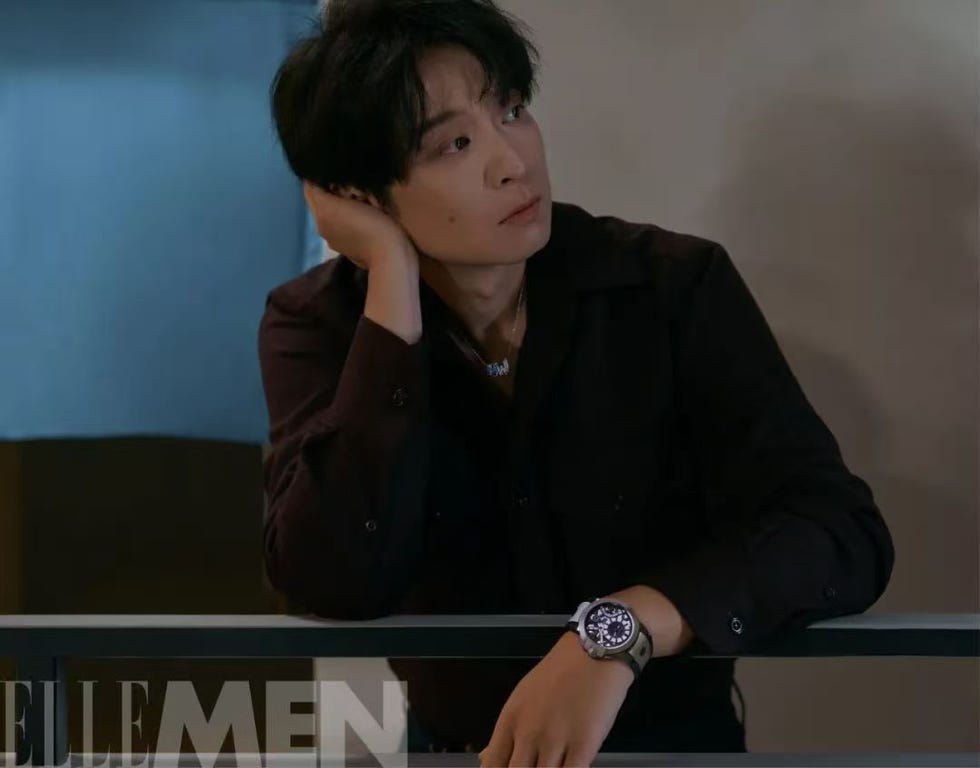 a person in a black shirt resting their chin on their hand while sitting