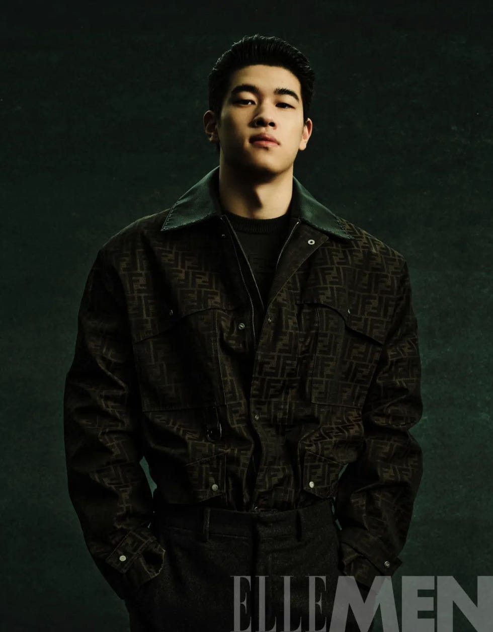 fashion model in a dark patterned jacket against a dark background