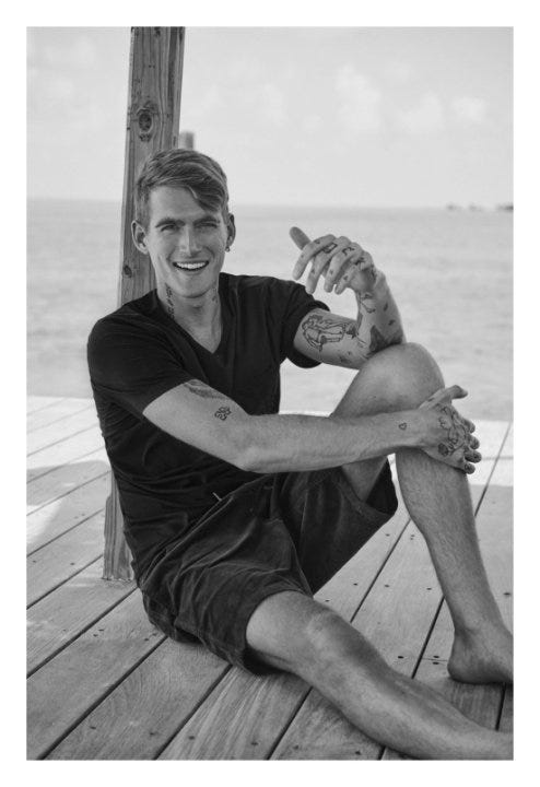 individual sitting on a wooden dock near the water