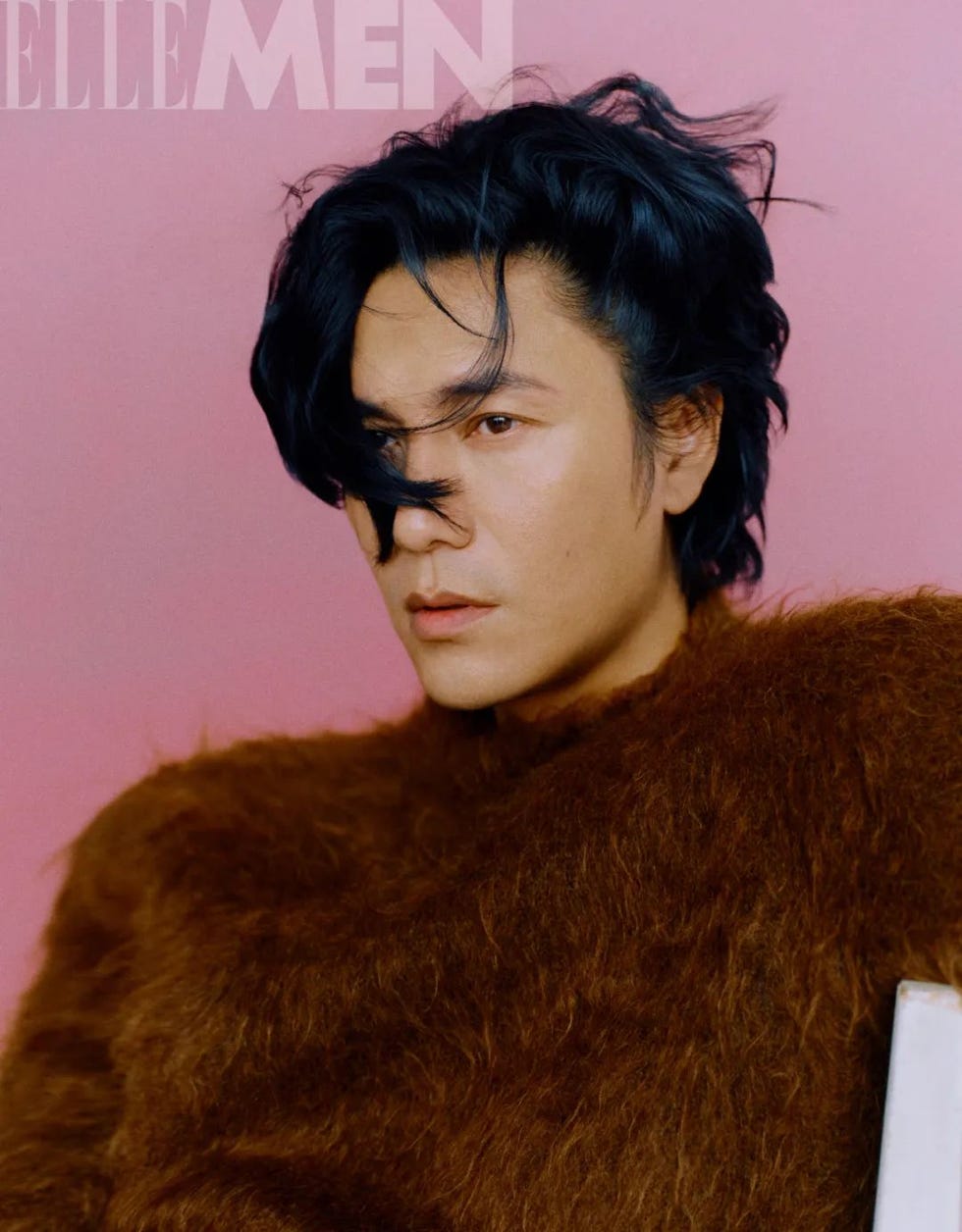 fashion portrait featuring a person in a fuzzy brown garment against a pink background