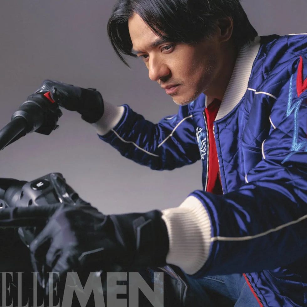 person in a blue bomber jacket holding motorcycle handlebars