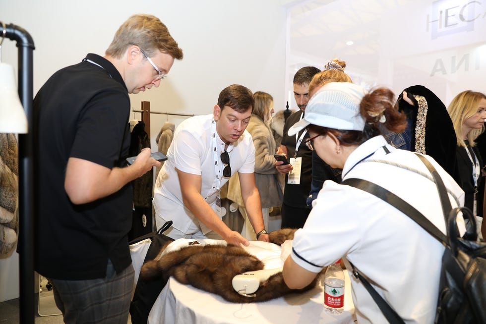 group of individuals engaged in examining fur garments at a display