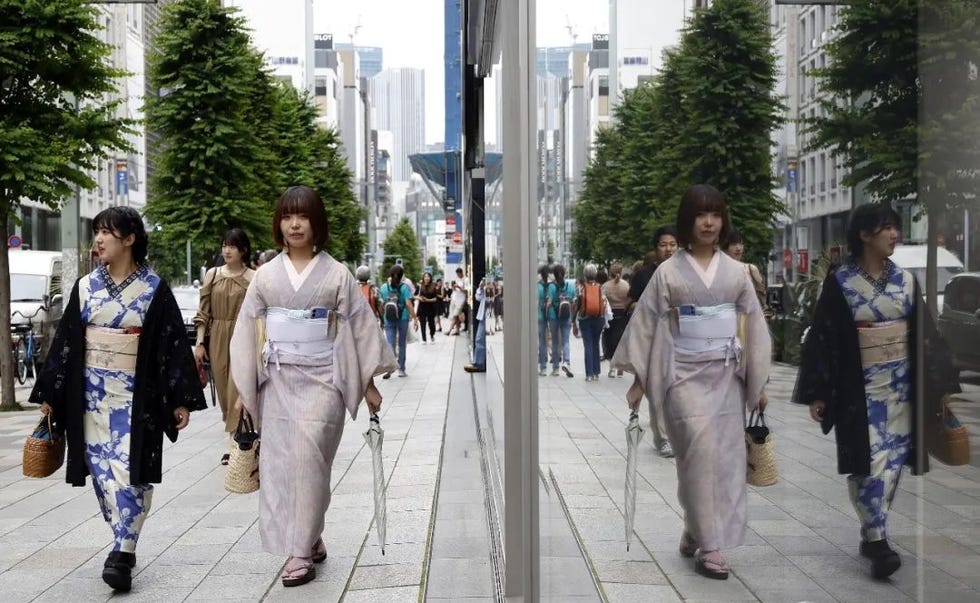 two women in traditional japanese attire walking in a bustling urban environment
