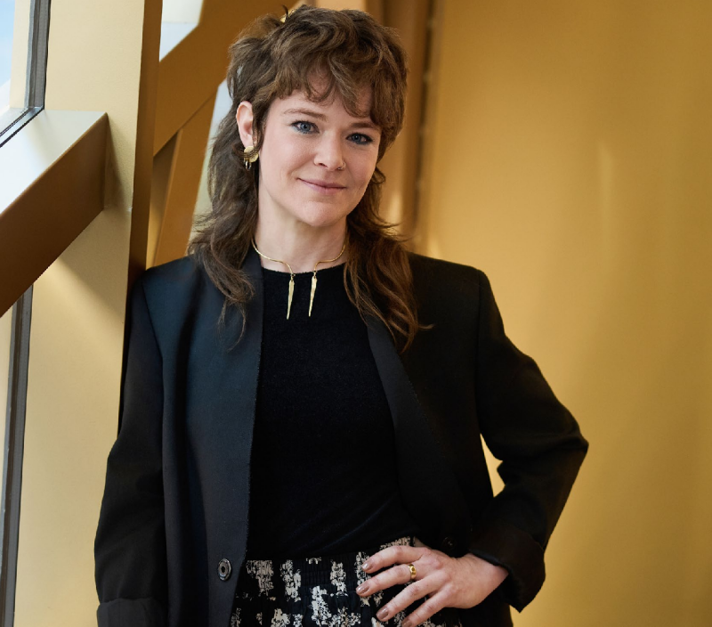 a person leaning against a wall dressed in a blazer with a stylish outfit