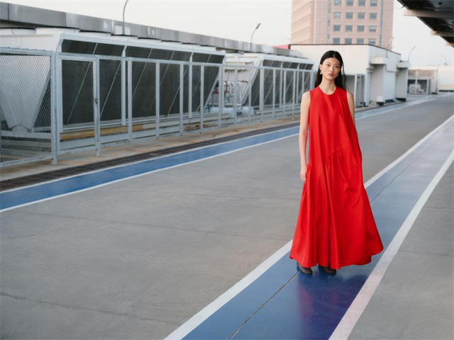 woman wearing a long red dress on a rooftop walkway