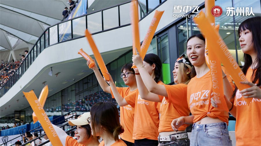 cheering fans wearing orange shirts and holding up orange foam sticks