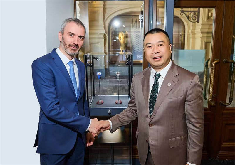 handshake between two men in a formal setting with display cases in the background