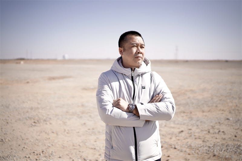 person standing in a barren landscape wearing a light jacket and wristwatch