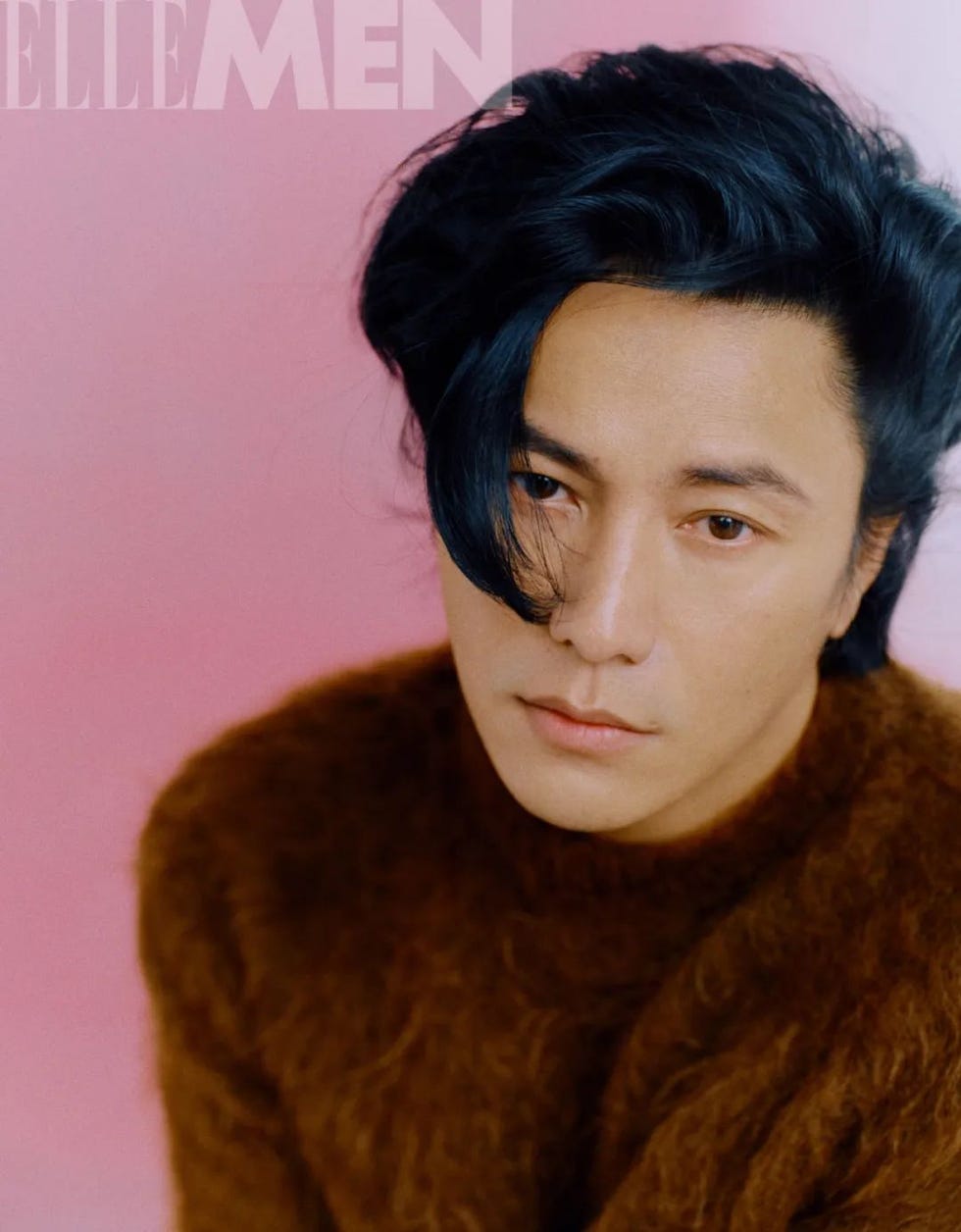 portrait of a person wearing a brown sweater against a pink background