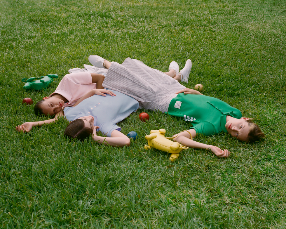 three individuals lying on lush green grass surrounded by colorful toys
