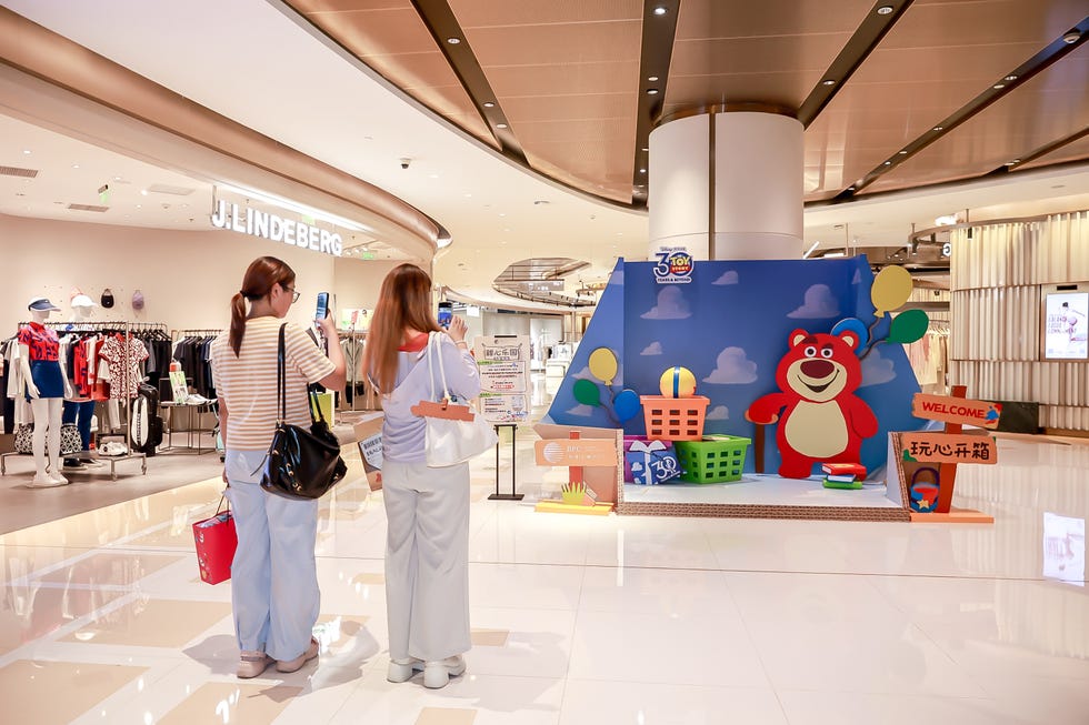 shoppers interacting with a promotional display in a shopping mall