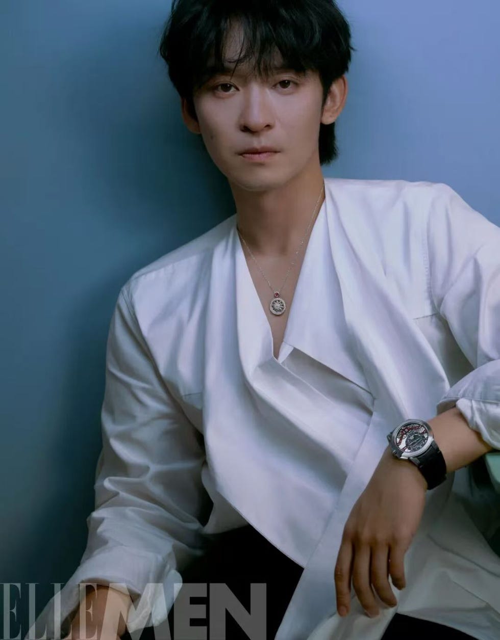 a person in a stylish white shirt with jewelry and a watch