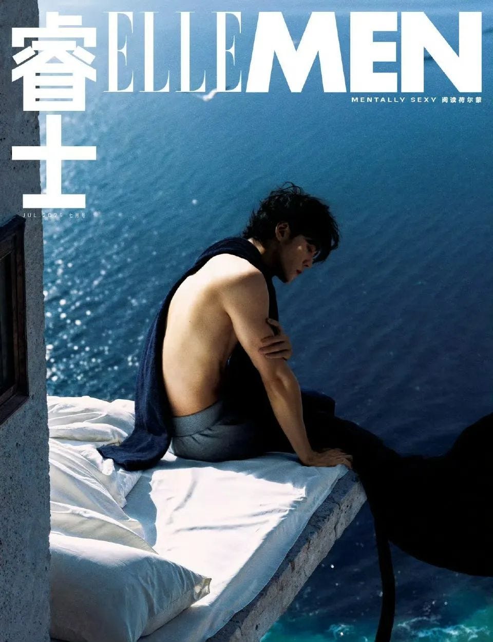 a model sitting on a ledge with an ocean backdrop featuring a magazine cover