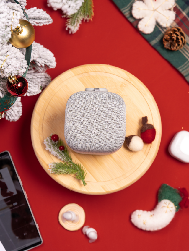 bluetooth speaker positioned on a wooden cutting board amidst holiday decorations