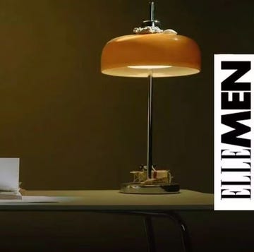 man sitting at a table with folded hands beside a lamp and a stack of papers man sitting at a table with folded hands beside a lamp and a stack of papers