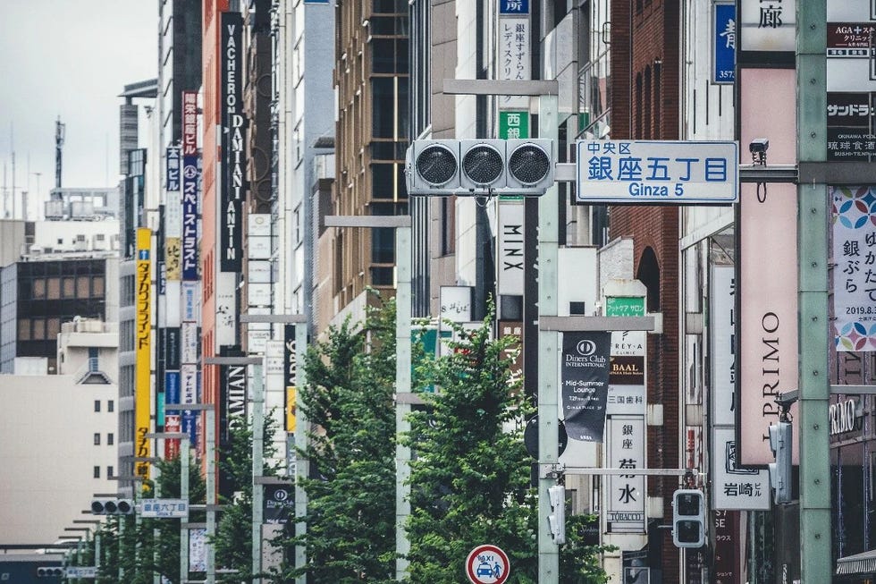 busy urban street in ginza tokyo with multiple shop signs and traffic lights