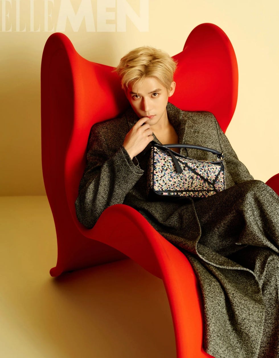 a person sitting on a red chair holding a stylish bag