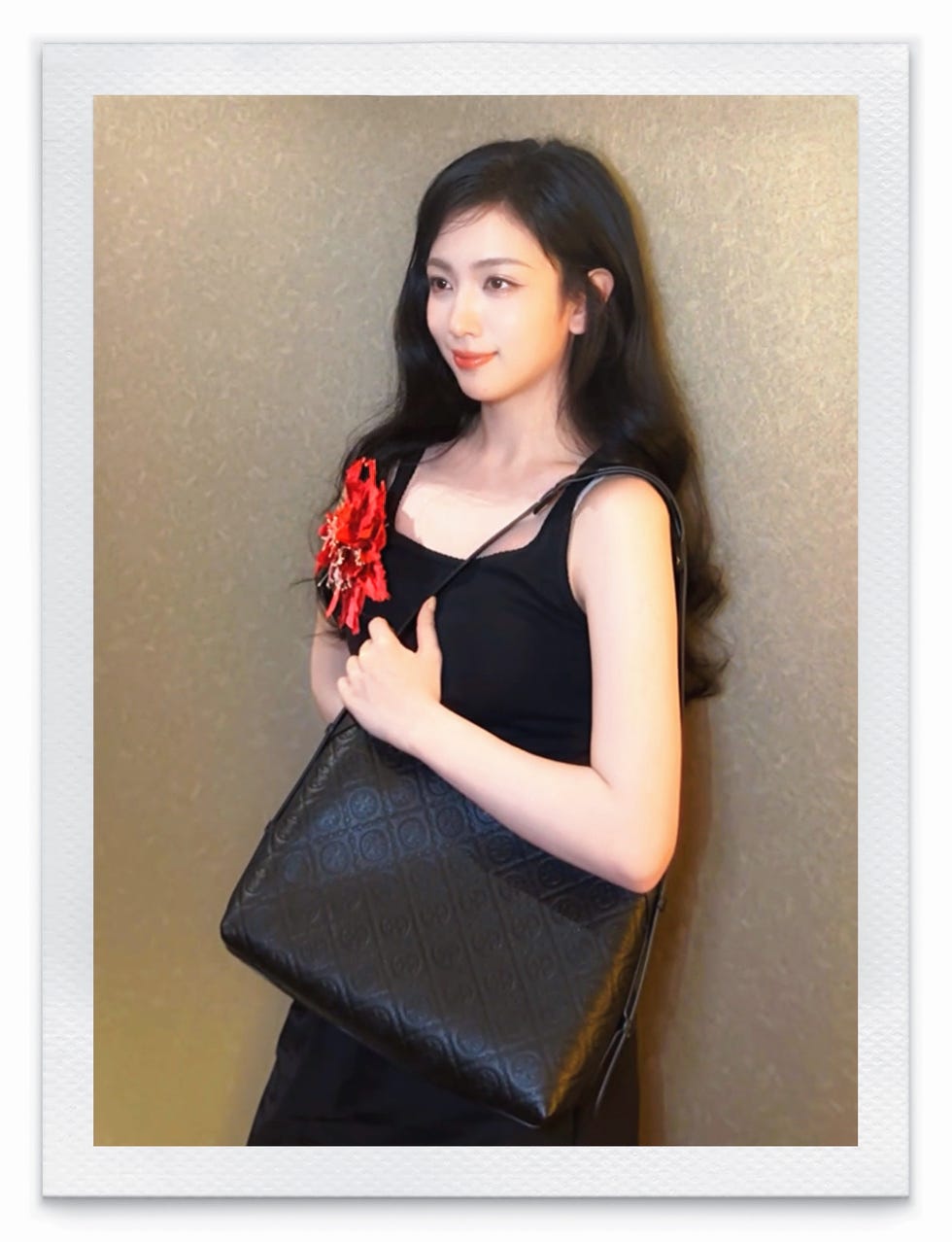 young woman holding a black handbag adorned with a red accessory